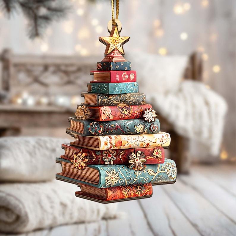 K&ouml;nnte beinhalten: Ein Weihnachtsbaumschmuck aus gestapelten, dekorativen B&uuml;chern. Die B&uuml;cher sind in verschiedenen Farben bemalt, darunter Rot, Blau und Gold, und mit floralen und sternf&ouml;rmigen Akzenten verziert. Ein Holzstern kr&ouml;nt den Baum, aufgeh&auml;ngt an einem goldenen Faden.