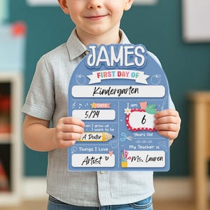 May include: A light blue, personalized first day of Kindergarten sign. The sign has the name "JAMES" at the top, with sections for date, age, and teacher's name. It also includes the text "Things I Love: Artist".