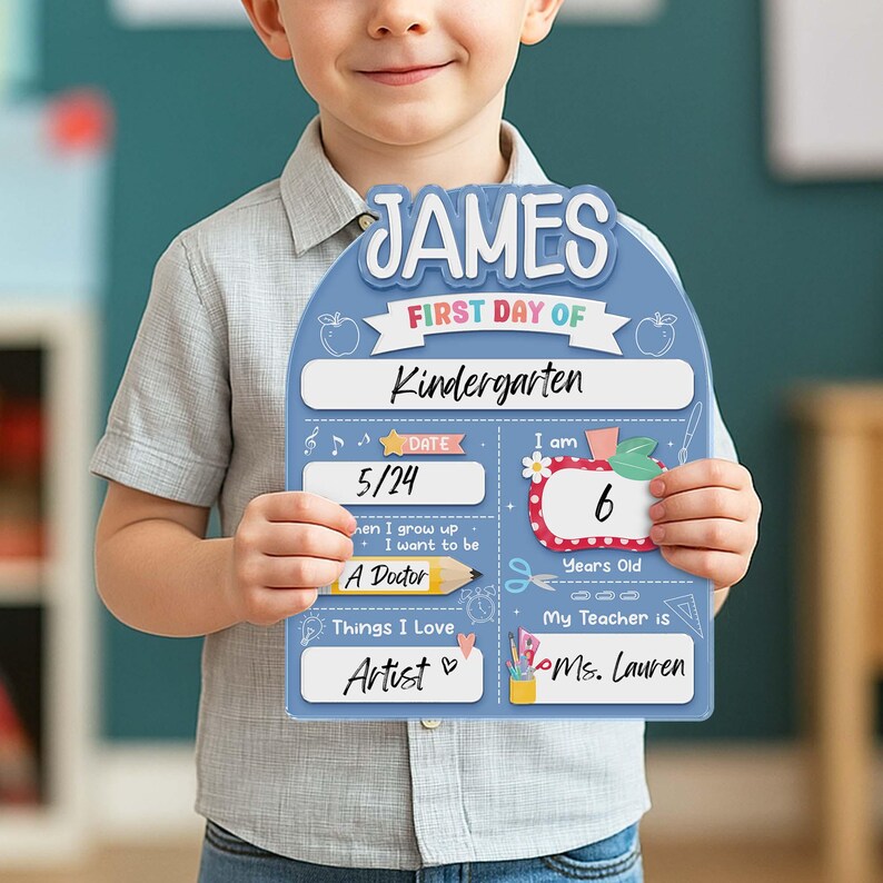 May include: A light blue, personalized first day of Kindergarten sign. The sign has the name "JAMES" at the top, with sections for date, age, and teacher's name. It also includes the text "Things I Love: Artist".
