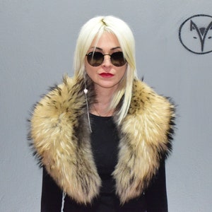 Puede incluir: Una mujer con cabello rubio que lleva gafas de sol y un cuello de piel. El cuello es de color marrón claro con puntas negras.