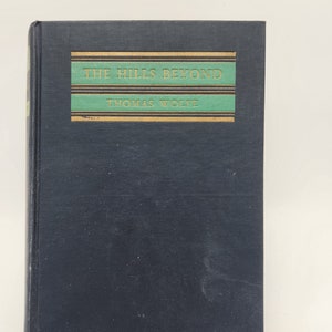 May include: A black hardback book with gold lettering on the spine. The title is "The Hills Beyond" by Thomas Wolfe.