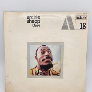 Könnte beinhalten: Ein weißes Vinyl-Albumcover mit einem Schwarzweißfoto von Archie Shepp. Der Albumtitel lautet "Archie Shepp - Blase" und das Plattenlabel ist "Actuel 18".