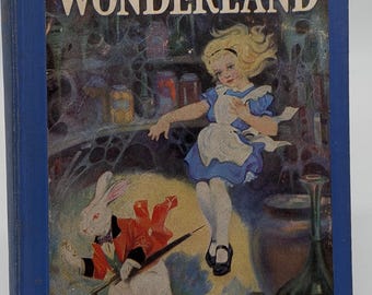 Puede incluir: Un libro antiguo de tapa dura titulado "ALICE IN WONDERLAND" con una cubierta azul. La ilustración de la portada representa a Alicia con un vestido azul, un conejo blanco con un abrigo rojo y varios elementos fantásticos. El título del libro está en letras blancas grandes.