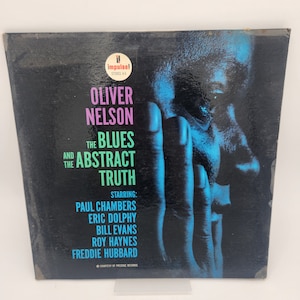 Może przedstawiać: Czarno-biała okładka albumu z niebiesko-zielonym portretem Olivera Nelsona. Tytuł albumu to "The Blues and the Abstract Truth" z tekstem "Starring: Paul Chambers, Eric Dolphy, Bill Evans, Roy Haynes, Freddie Hubbard".