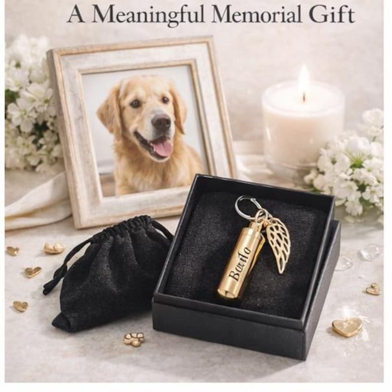 May include: A memorial gift set featuring a framed photo of a golden retriever, a small gold-colored urn with the name "Bardo", a gold wing charm, a black velvet bag, and a lit candle. The text at the top reads "A Meaningful Memorial Gift."