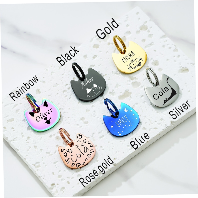 May include: Six cat-shaped pet ID tags in rainbow, black, gold, silver, blue, and rose gold finishes. Each tag features a metal jump ring and custom engraved names and graphics, including Oliver, Asher, Misha, Cola, Emily, and Cola with heart patterns.