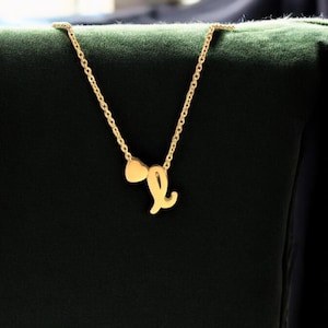 Puede incluir: Un collar de oro con un dije de corazón y una letra L.