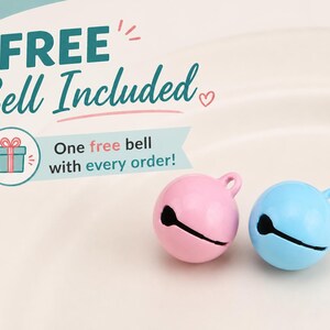 May include: Two small spherical jingle bells, one pastel pink and one light blue, each featuring a top loop and a horizontal slit. Text on the image reads: FREE Bell Included, One free bell with every order! with a small gift box icon.