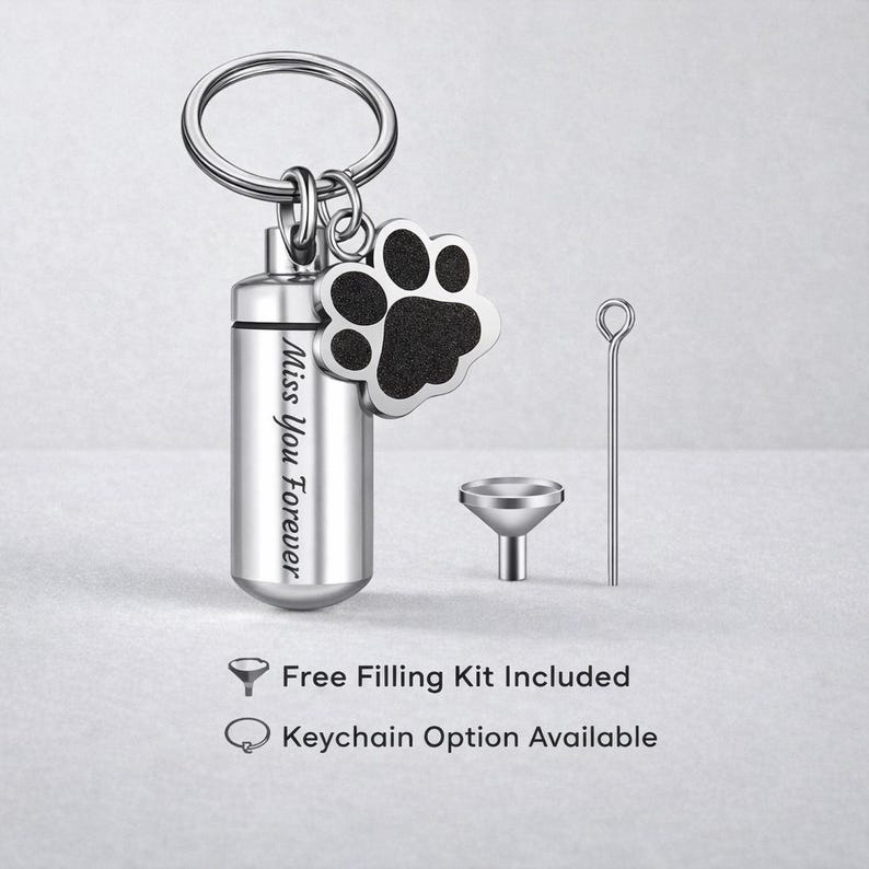 May include: A silver-colored pet urn keychain with a paw print charm. The urn is cylindrical and engraved with "Miss You Forever." A small funnel and filling tool are included. The keychain is designed for pet memorial keepsakes.