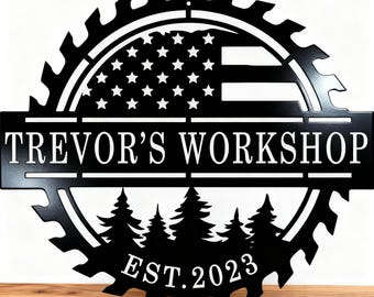 May include: A black metal circular wall sign shaped like a saw blade. The top half features an American flag design, while the bottom half displays a forest of pine trees. The text reads TREVOR'S WORKSHOP and EST. 2023 in white lettering.
