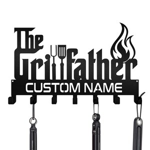 May include: Black metal wall-mounted hook rack with the text "The Grillfather" and a space for a custom name. The rack has six hooks and a flame design.