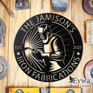 May include: Black and white circular metal sign with the text "The Jamison's Iron Fabrications Est. 2025" and a silhouette of a welder with a welding torch.