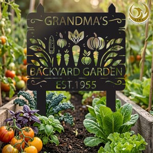 May include: Black metal garden sign with the words "GRANDMA'S BACKYARD GARDEN EST. 1955" and vegetable cutouts. The sign is in a garden bed with tomatoes and lettuce.