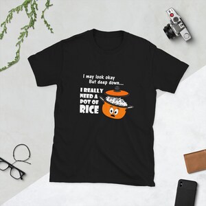 May include: Black t-shirt with the text "I may look okay, but deep down... I REALLY NEED A POT OF RICE." The shirt features a cartoon image of an orange pot with rice and a lid.