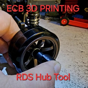 May include: A black 3D printed tool for removing and installing hub wheels on a remote control car. The tool is labeled "RDS Hub Tool".