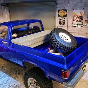 Puede incluir: Una camioneta azul con una llanta de repuesto en la caja. La camioneta tiene una caja de herramientas en la caja y una pegatina en el lateral que dice "MIP".