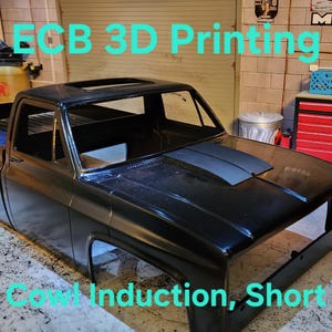 Pode incluir: Modelo preto impresso em 3D de uma pick-up com capô de indução cowl. Os textos "ECB 3D Printing" e "Cowl Induction, Short" são visíveis. O modelo está sobre uma superfície de concreto.