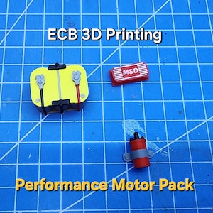 以下が含まれることがあります： 模型車用の3Dプリントされたパフォーマンスモーターパック。パックには、黄色のバッテリー、赤いMSDイグニッションボックス、灰色のワイヤーが付いた赤いコイルが含まれています。画像には、「ECB 3D Printing」と「Performance Motor Pack」のテキストが表示されています。
