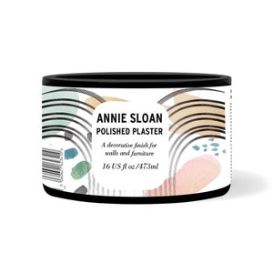 May include: A white can with black lettering that reads "ANNIE SLOAN POLISHED PLASTER" and "A decorative finish for walls and furniture 16 US fl oz/473ml". The can has a black lid and is decorated with abstract shapes in shades of blue, green, pink, and brown.