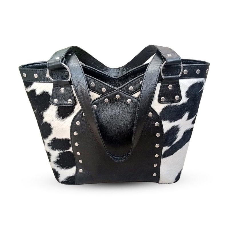 May include: Black and white cowhide tote bag with black leather accents and silver studs.