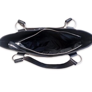 May include: Black leather tote bag with silver hardware and a zipper closure. The bag is open and the inside is visible.