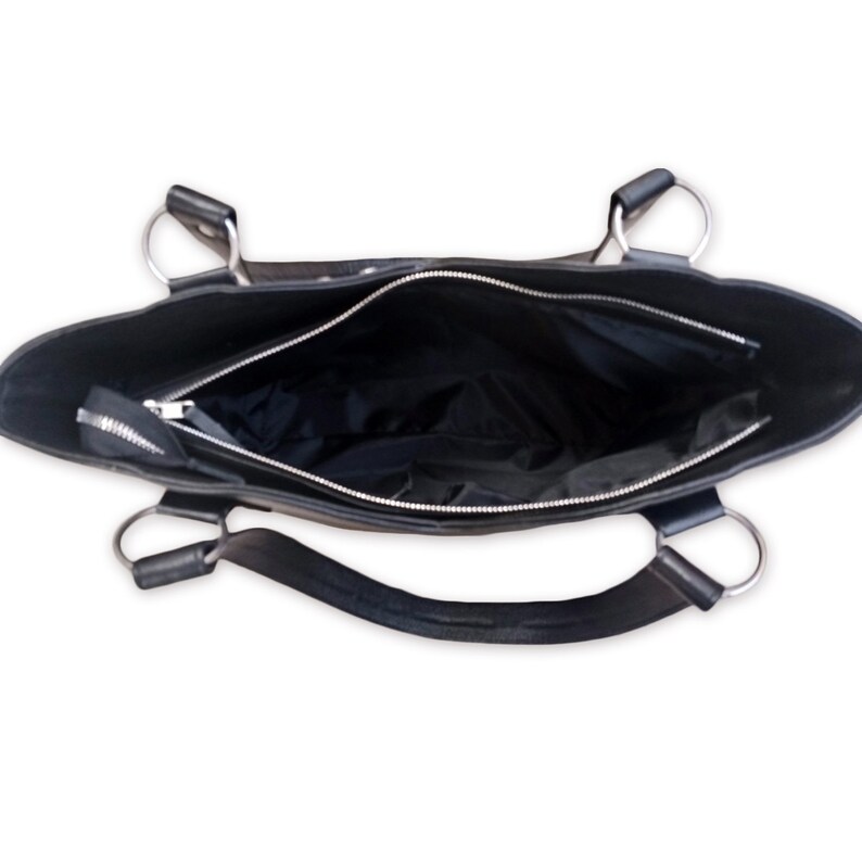 May include: Black leather tote bag with silver hardware and a zipper closure. The bag is open and the inside is visible.