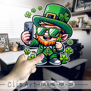 Op de afbeelding: Een cartoon-kabouter met een groene hoed, zonnebril en een groen pak. Hij houdt een smartphone vast en glimlacht. Er zijn klavertjes vier om hem heen.