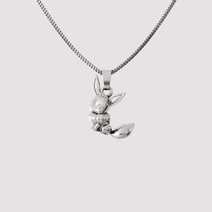 Op de afbeelding: Een zilverkleurige metalen ketting met een hanger in de vorm van een klein, gebeeldhouwd vosachtig wezen met grote oren en een pluizige staart. De hanger hangt aan een fijne, dunne zilverkleurige ketting met een klassiek schakelontwerp.