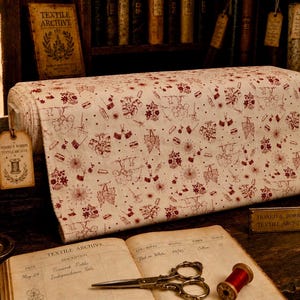 May include: A bolt of off-white fabric featuring a repeating pattern of dark red illustrations including fireworks, trees, and small figures. The fabric is displayed with a tag labeled Hoard & Bobbin Textile Archive, alongside a vintage book, scissors, and a spool of red thread.