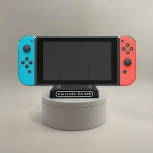 May include: A blue and red Nintendo Switch console on a white stand with the text "Nintendo Switch" on the front.