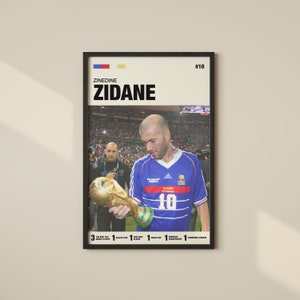 May include: A vintage-style poster featuring a photo of Zinedine Zidane holding the World Cup trophy. The poster is black and white with a red, white, and blue French flag in the top left corner. The text "Zinedine Zidane" is in bold black letters and the number "10" is in the top right corner. The poster lists Zidane's accomplishments, including "3 The Best FIFA Men's Player", "1 Ballon d'Or", "1 FIFA World Cup", and "1 European Championship".