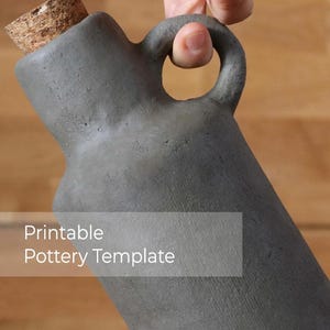 May include: A grey ceramic bottle with a cork stopper and a handle. The bottle is a printable pottery template.