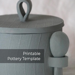 May include: A grey ceramic pottery template with a lid and a handle. The template is for a round container with a knob on the side. The text "Printable Pottery Template" is printed on the front of the template.