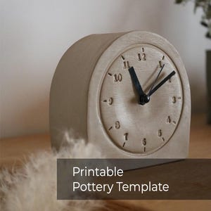Puede incluir: Un reloj beige y redondeado con manecillas negras y números en relieve. La esfera del reloj tiene los números del 1 al 12. El texto "Printable Pottery Template" se muestra en un rectángulo oscuro en la parte inferior de la imagen.