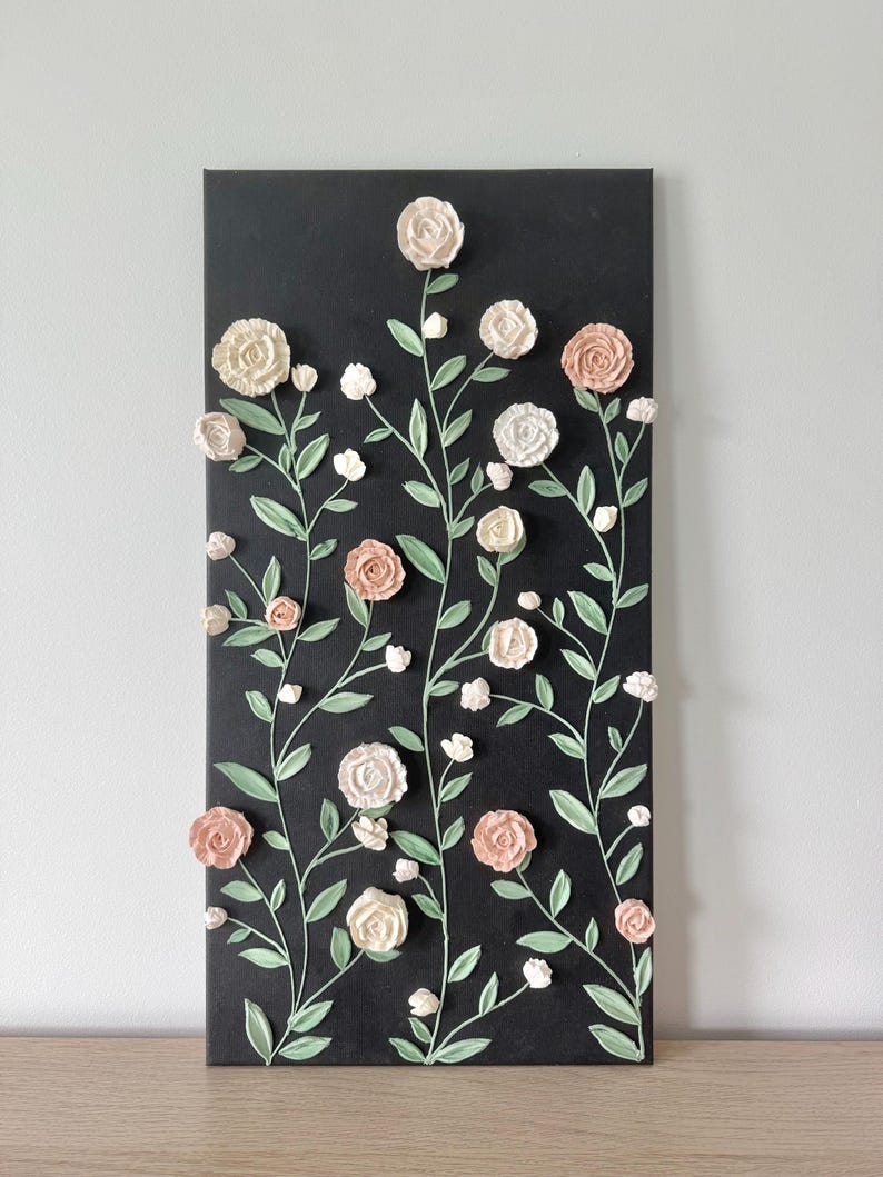 12 x 24 inch wall art on canvas with a charcoal gray background and 3D textured ivory and blush roses and green stems and leaves. The roses are piped and adhered with acrylic modeling paste.
