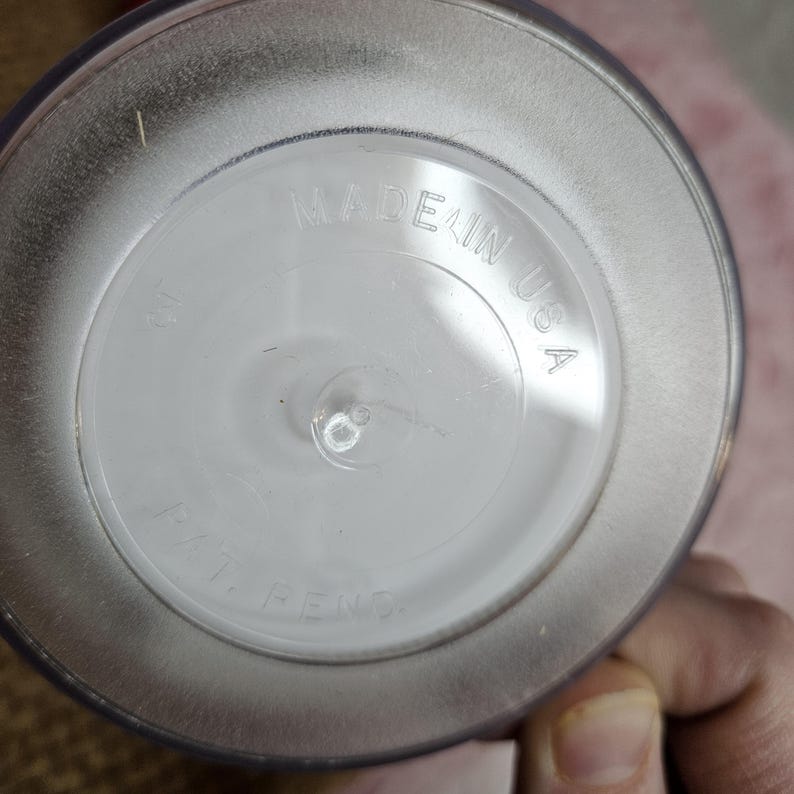 Pu&ograve; includere: Primo piano del fondo di un barattolo di vetro trasparente con le parole "MADE IN USA" stampate sul fondo.