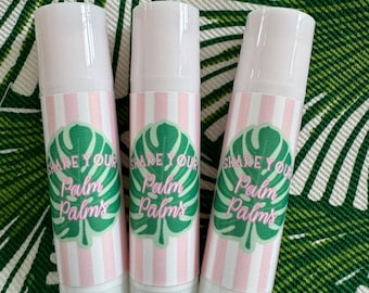 May include: Three white lip balm tubes with pink and white striped labels. Each label has a green palm leaf design and the text "Shake Your Palm Palms".
