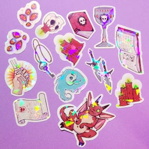 May include: A collection of holographic stickers featuring fantasy and occult themes. Designs include a skull, a chalice, a book, a key, a scroll, a demon, candles, a ghost, a hand holding bones, and swords. The stickers have a purple background.