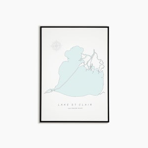 May include: A framed print featuring a light blue map of Lake St. Clair. The map is set against a white background, with the lake's outline and surrounding waterways clearly defined. The text "LAKE ST. CLAIR" and "-430 SQUARE MILES" are printed below the map.