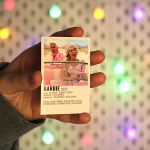 Pu&ograve; includere: Un poster di film rosa e bianco per il film "Barbie", uscito nel 2023. Il poster presenta una foto di Margot Robbie e Ryan Gosling in una macchina convertibile rosa. Il testo sul poster recita "Avventura Commedia Fantasy", "Greta Gerwig", "Tom Ackerley", "Greta Gerwig", "Margot Robbie", "Ryan Gosling", "Issa Rae", "Kate McKinnon", "Alexandra Shipp" e "Emma Mackey".
