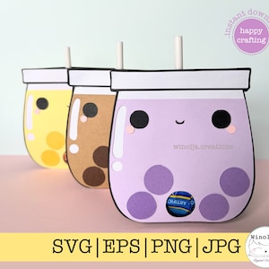 May include: Three paper craft bubble tea cups with straws. The cups are yellow, brown, and purple with black eyes and a smiling mouth. The purple cup has a clear circle cut out to hold a small candy. The cups are on a pink surface with a yellow surface below.