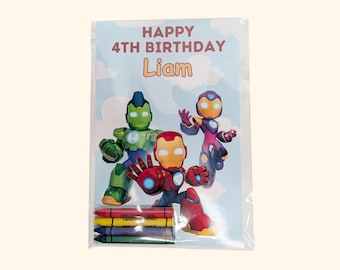 May include: A rectangular birthday card featuring the text HAPPY 4TH BIRTHDAY Liam, illustrated with three stylized robotic figures in red, green, and purple against a light blue cloudy sky, packaged with four colored crayons at the bottom.