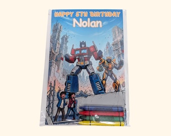 May include: A rectangular plastic-wrapped coloring activity sheet featuring the text HAPPY 5TH BIRTHDAY Nolan, with illustrations of two robots and two children in a city setting, accompanied by four wax crayons in blue, red, green, and yellow.
