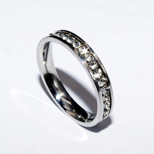 May include: A silver band ring with a row of clear cubic zirconia stones.