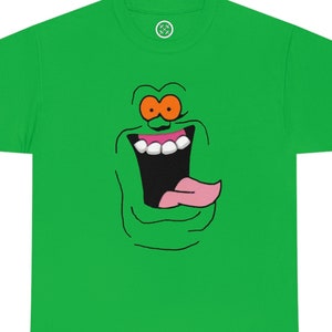 以下が含まれることがあります： 緑色のTシャツに、口を大きく開けてピンクの舌を出した緑色の幽霊の顔が描かれています。幽霊はオレンジ色の目と白い歯をしています。