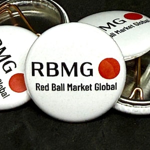 May include: White button pins with the text "RBMG Red Ball Market Global" in black font. Each pin features a red circle. The pins are round and have a metal backing.