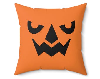 May include: Orange throw pillow with a black jack-o'-lantern face design.