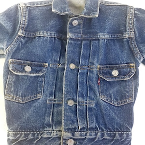 May include: A blue denim jacket with a button fastening and two front pockets. The jacket has a faded look and is in good condition.