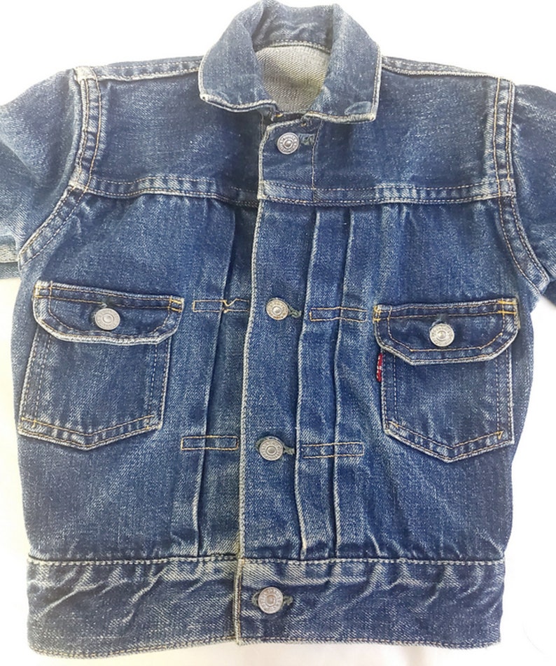 May include: A blue denim jacket with a button fastening and two front pockets. The jacket has a faded look and is in good condition.