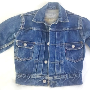 May include: A vintage blue denim jacket with a button closure, two chest pockets, and long sleeves.